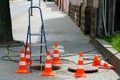 Orange cones installed around the dangerous area on the sidewalk. An open travel hatch. Laying of a new fiber-optic cable in the Royalty Free Stock Photo