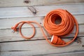 Orange construction electrical extension cord coiled on wood texture background Royalty Free Stock Photo