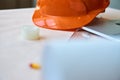 Orange construction helmet on the table, adhesive tape, paper for drawings Royalty Free Stock Photo