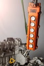 Orange control panel for a crane in an in-booster production or in a car service with buttons for moving in different directions