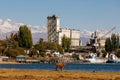 orange cow is grazing in front of old abandoned soviet Port Balykchy on Issyk-Kul lake at sunny autumn afternoon