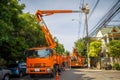 An orange crane lift sending workman with safety on a bucket to repair a light pole in the village