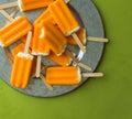 Orange creamsicle popsicles on a galvanized steel platter, on a green background shot directly above, top view. Copy space. Royalty Free Stock Photo