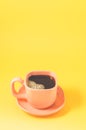 Orange cup with a saucer full of black coffee on a yellow background/orange cup of espresso with a skin on a yellow background Royalty Free Stock Photo