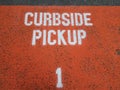 orange curbside pickup sign on asphalt or ground with the number 1