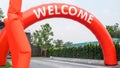 Orange curve balloon with white text WELCOME and fan blowing balloons in advertising in front of village entrance Royalty Free Stock Photo