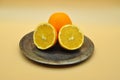 An orange cut in half and a whole orange placed on an elegant and antique silver plate Royalty Free Stock Photo