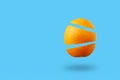 Orange cut into three parts on a blue background - Levitation of summer orange fruit - Minimal creative composition with copy