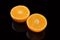 Orange cut into two pieces, on a black background. Royalty Free Stock Photo