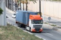 And orange DAF XF truck loading a blue container trailer along Barcelona's Ronda Litoral