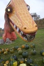Orange Dinosaur Eyes Peer at Pumpkin Patchgoers