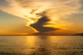 Orange dramatic sunrise over the sea with bank of dark clouds on the sky in Naoussa Village on Paros Island, Greece.