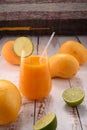 Orange drink closeup with lime slice on white vintage wooden desktop with mangos Royalty Free Stock Photo