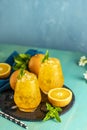 Orange drink with ice. Two glass of orange ice drink with fresh mint on wooden turquoise table surface.