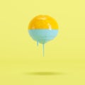 Orange dripping in blue paint on pastel yellow background Royalty Free Stock Photo