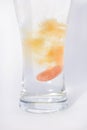 Orange effervescent tablet in glass of water