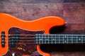 Orange electric bass guitar on wood