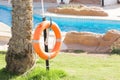 Orange emergency lifebuoy hanging on fence near pool on vacation at the hotel with copy space