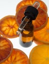 Orange essential oil in amber bottle with red oranges Royalty Free Stock Photo