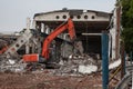 Orange excavator demolishes an old industrial building
