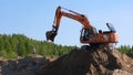 Orange excavator excavates sand at a construction site: Moscow, Russia - August 30, 2021