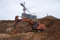 Orange excavator machine on earthworks in sandpit at construction site. Backhoe digs ground for construct foundantion and laying Royalty Free Stock Photo