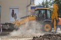 Orange excavator on wheels works in the city