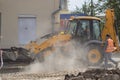 Orange excavator on wheels works in the city