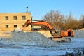 Excavator working on an industrial building site, loading plaster stone with a loader bucket Royalty Free Stock Photo