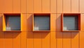 Orange facade of modern building with three square windows. Exterior clad with decorative panels creating geometric pattern. Royalty Free Stock Photo