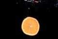 An orange falling into water on a black shiny background falls under water with bubbles Royalty Free Stock Photo