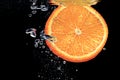 An orange falling into water on a black shiny background falls under water with bubbles Royalty Free Stock Photo