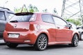 Orange Fiat Grande Punto three door hatchback parked on the street in the city