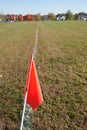 An orange flag on a painted white boundary line on a large grassy athletic field