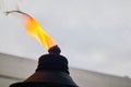 orange flame and burning wick on an oil torch against an overcast sky in the backyard