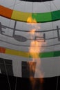 An orange flame fills the inside of a colorful hot air balloon with heat in preparation for take off Royalty Free Stock Photo