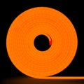 Orange flexible glowing led tape neon in reel standing on black background