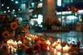 Orange flowers and candles on an urban sidewalk at night, spontaneous memorial