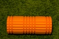 Orange foam roller on green background Royalty Free Stock Photo