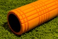 Orange foam roller on green background Royalty Free Stock Photo