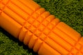 Orange foam roller on green background