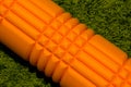 Orange foam roller on green background Royalty Free Stock Photo