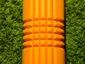 Orange foam roller on green background Royalty Free Stock Photo