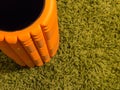 Orange foam roller on green background Royalty Free Stock Photo