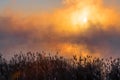 An orange fog spreads over the water and obscures the horizon.  Sunset Sunrise time over the winter river Royalty Free Stock Photo