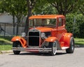 Orange 1929 Ford Model A Coupe restored with racing tires and engine parked on a residential street in Dallas, Texas.