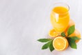 Orange fresh citrus juice with ripe oranges and green leaf on soft white wood board, border, top view. Royalty Free Stock Photo