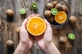 Orange fruit in female hands on a blurred wooden background, top view. Royalty Free Stock Photo