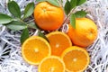 Orange fruit pile and half piece with green leaves fruits or vegetables on white shredded paper closeup Royalty Free Stock Photo