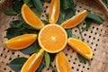 Orange fruit pile half and slice with green leaves fruits or vegetables on wicker tray 